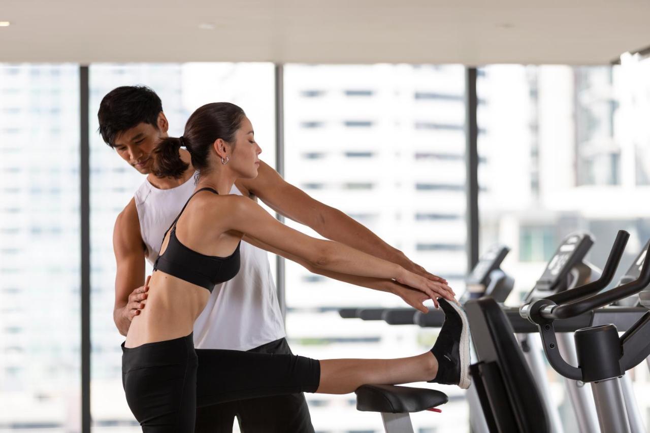 Ascott Thonglor Bangkok - SHA Plus Certified Kültér fotó A personal trainer assisting a woman with a stretching exercise